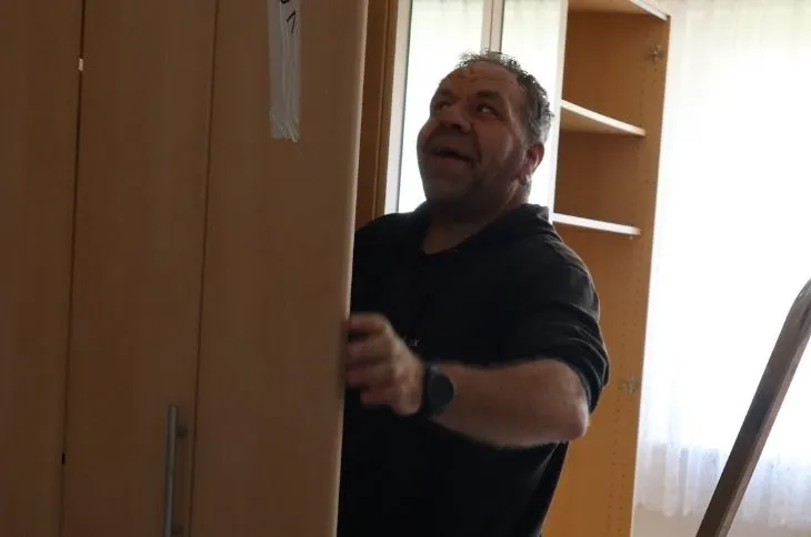 umzugshelfer traegt schrank im innenraum